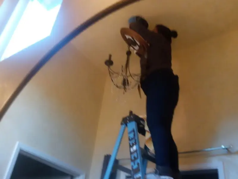 Electrician installing a chandelier in a Blair residence